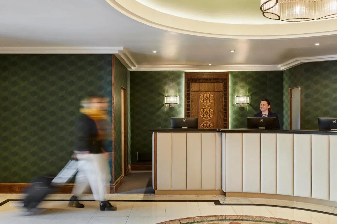 a person walking past a counter in a hotel lobby at The Clermont London, Charing Cross in London