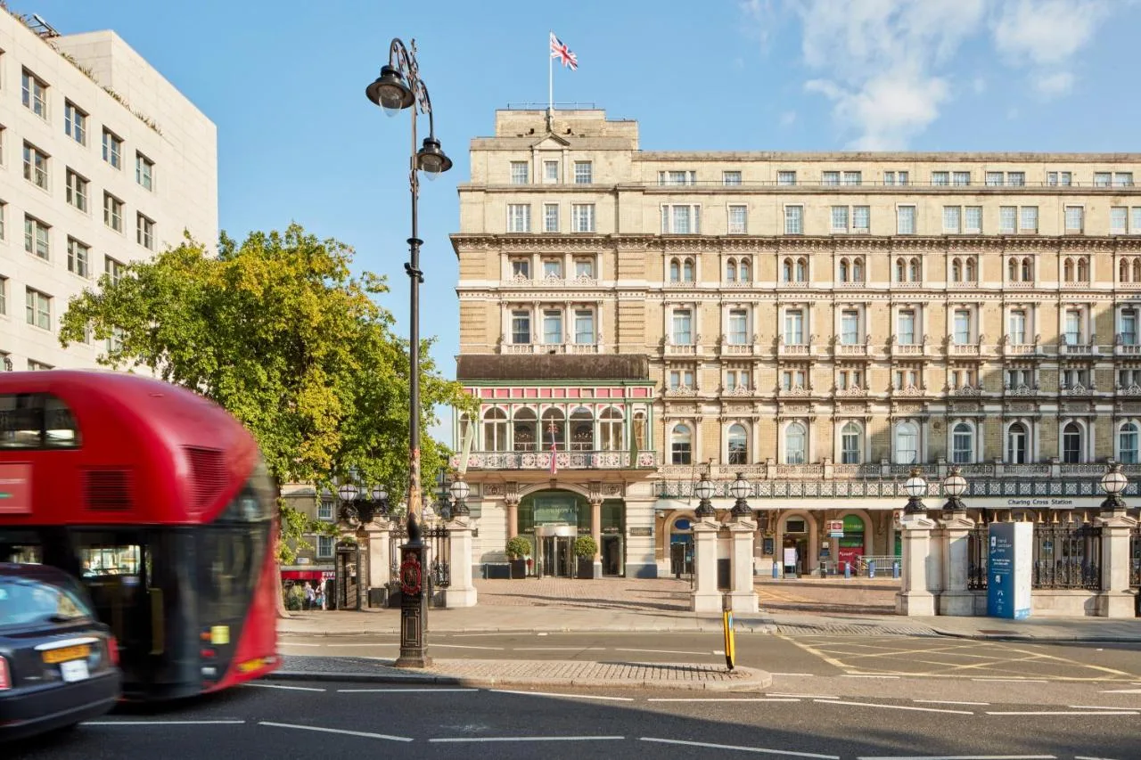 a red bus driving down a street in front of a building at The Clermont London, Charing Cross in London
